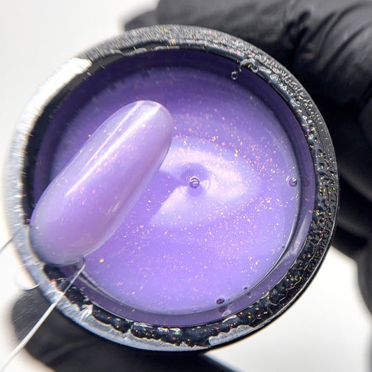 Purple candle being held by a gloved hand with a white background