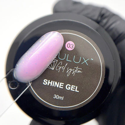 Nail polish with a gloved hand holding a bottle labeled 'Julux Shine Gel' on a white background.